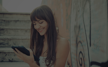 Woman looking down at a tablet device with a smile